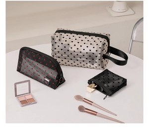 Close-up of mesh makeup bags with flocked heart patterns in beige and black