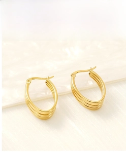 Macro view of triple-layered wavy golden hoop earrings on elegant fabric display