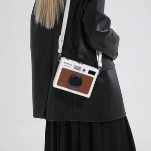 Retro camera-shaped crossbody bag in white with brown leather trim and professional styling