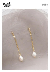 Detail of long gold chain earrings featuring white freshwater pearl drops and stud