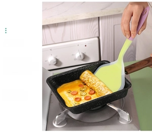 Spatule en silicone retournant une omelette dans une poêle tamagoyaki antiadhésive en pierre