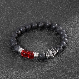 Detail of black lava stone beads with a silver Hamsa Hand charm on a beaded bracelet