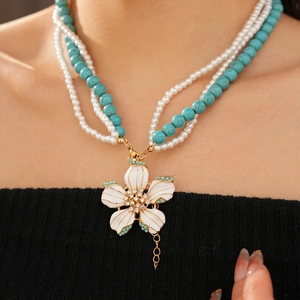Détail d'un collier de perles avec pendentif fleur et accents turquoise élégants