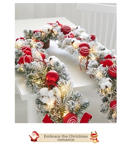 Close-up of lighted white flocked Christmas garland with red bows and cotton balls