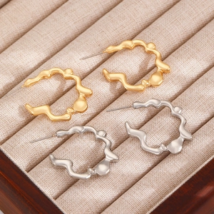 Macro shot of liquid metal style C-shaped earrings in polished gold and silver finishes