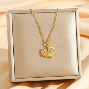 Collier cœur doré avec zircon sur un écrin à bijoux en soie de couleur champagne