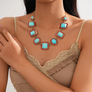 Close-up of bohemian sweater necklace with turquoise stones and red bead accents