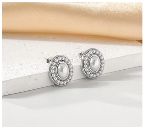 Close-up of elegant oval silver earrings with a large white pearl and halo on satin