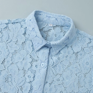 Close-up of light blue lace shirt collar featuring intricate floral embroidery and buttons