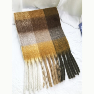 Close-up of warm brown and yellow plaid scarf with soft fringe details on fabric
