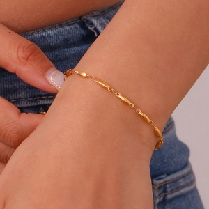 Detailed close-up of a delicate 18K gold-plated oval link bracelet on a model wrist