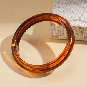 Macro shot of an amber acrylic bangle showing translucent texture and warm refraction
