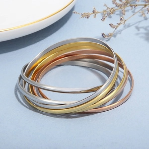 Macro view of multi-color stainless steel interlocking bangles in gold, silver and rose gold