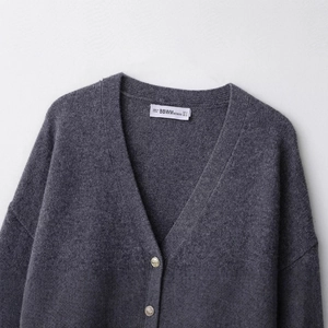 Vue de face du cardigan en laine grise avec boutons dorés et détails du col