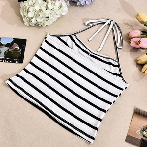 Flat lay di un crop top a righe con lacci sulla schiena su sfondo effetto sabbia