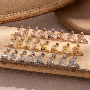 Detailed collection of assorted stainless steel cartilage studs on a textured stone surface