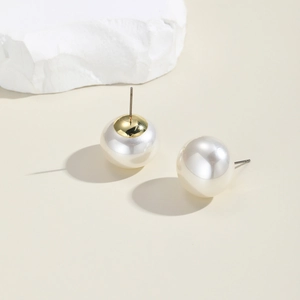 Macro shot of large pearl stud earrings with gold metal base on minimalist stone
