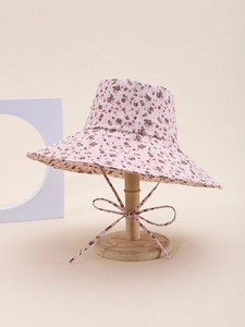 Detail view of pink floral wide-brim sun hat with adjustable ribbon bow on a stand