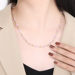 Detail of pink butterfly and gold bead necklace worn by a model in close-up shot