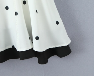 Détail du motif à pois et de l'ourlet noir superposé sur une robe élégante