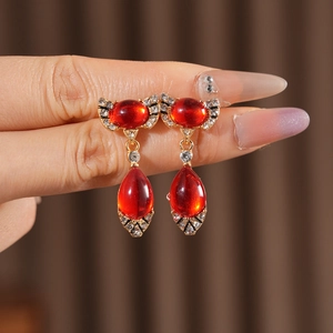 Close-up of vintage gold water-drop earrings with red gems and sparkling rhinestones