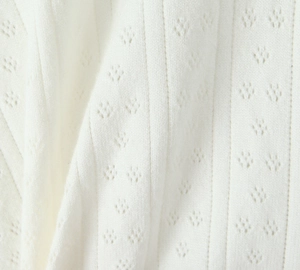 Gros plan sur un tissu en maille blanc avec des motifs floraux ajourés et côtelés