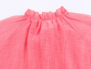 Close-up of pink ruffled stand-up collar and pleated fabric texture on a women blouse