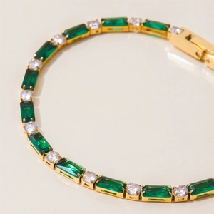 Detail of gold bracelet with emerald-cut green gems and round white cubic zirconia