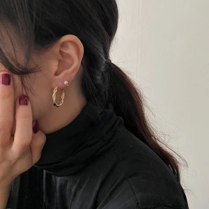 Close-up of model wearing gold twisted hoop earring and small white pearl stud set