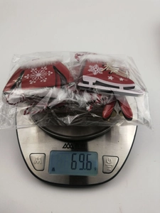 Digital scale showing the 69.6g weight of red wooden glove and skate Christmas ornaments