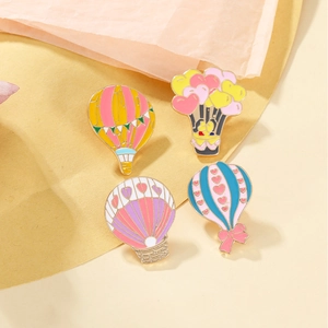 Detailed view of colorful hot air balloon enamel brooches in pink, blue, and yellow shades