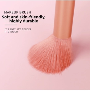 Detailed close-up of soft coral orange synthetic bristles and matte metal makeup brush handle