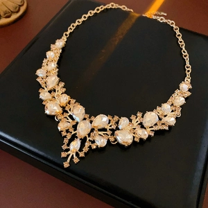 Detailed close-up of luxurious gold crystal flower necklace on black velvet gift box