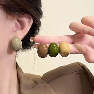 Detail showing various earth-toned oval resin stud earrings with glossy finish