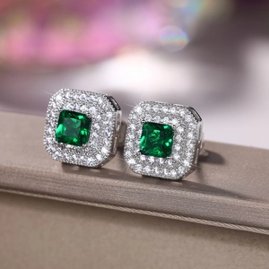 Macro detail of square emerald-cut green zircon stud earrings with double halo setting
