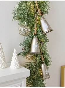Detail von goldenen Metallglocken mit Rentierdruck, Zapfen und LED-Kiefernnadeln