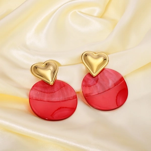 Exaggerated gold heart and red resin round drop earrings on elegant silk fabric