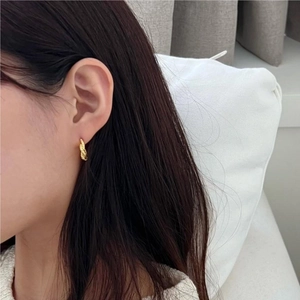Close-up of twisted 925 silver hoop earring in gold finish worn by a female model