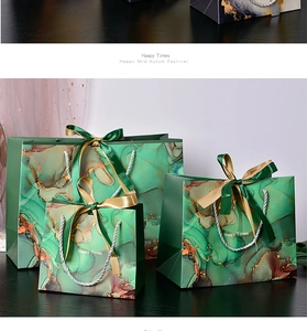 Detail of green marble gift bags with elegant ribbon bows and silver twisted handles