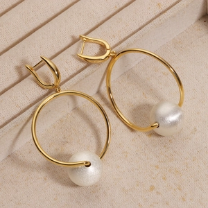 Detail of 18K gold plated hoop earrings with elegant white faux pearl charms