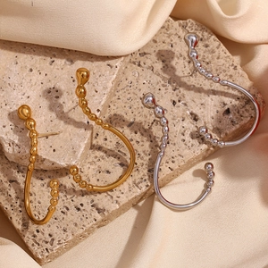 Artistic gold and silver wavy hook earrings displayed on stone and satin background