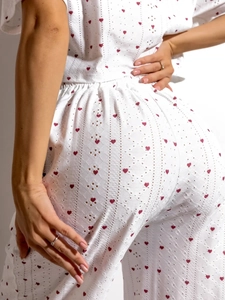 Détail du tissu blanc avec imprimés cœurs rouges et texture de broderie anglaise