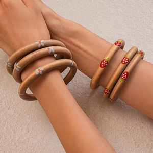 Macro detail of three-piece wooden bangles with daisy and strawberry floral prints