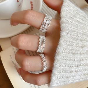Detailed view of silver hollow lace ring set with floral and heart motifs on model's hand