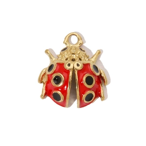Gros plan d'un pendentif coccinelle en émail rouge plaqué or 14k sur fond blanc