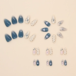 Elegant almond press-on nails with heart, bow, and polka dot patterns in navy and cream