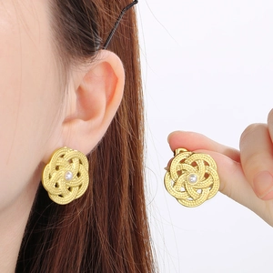 Détail de boucles d'oreilles fleurs ajourées dorées avec perle portées par un mannequin
