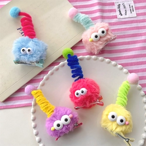 Detailed view of colorful plush monster hair clips with large eyes and metal duckbill clips