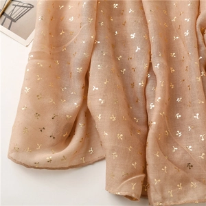 Detail of nude linen-feel scarf featuring gold foil cherry patterns and soft texture