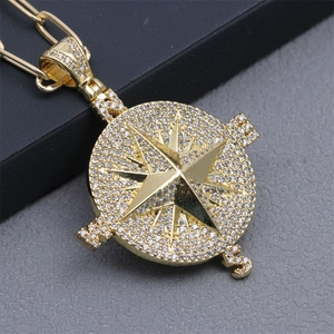 Macro shot of gold compass pendant with micro-pave cubic zirconia and star detail